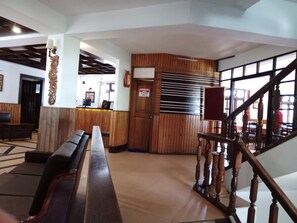 Eine Lobby mit einer Rezeption, Holzbänken, einer Treppe und einem Schild, das einen Zugangsbeschränkten Bereich kennzeichnet.
