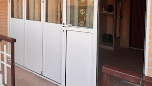 A sliding glass door with a view of a brick building and a tiled floor. - la villetta fiera airport (Rome)