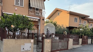 A residential area with two brick houses, a gated entrance, and a small garden. - la villetta fiera airport (Rome)