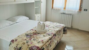 A bedroom with a bed, a wardrobe, a radiator, and a window with curtains. - la villetta fiera airport (Rome)