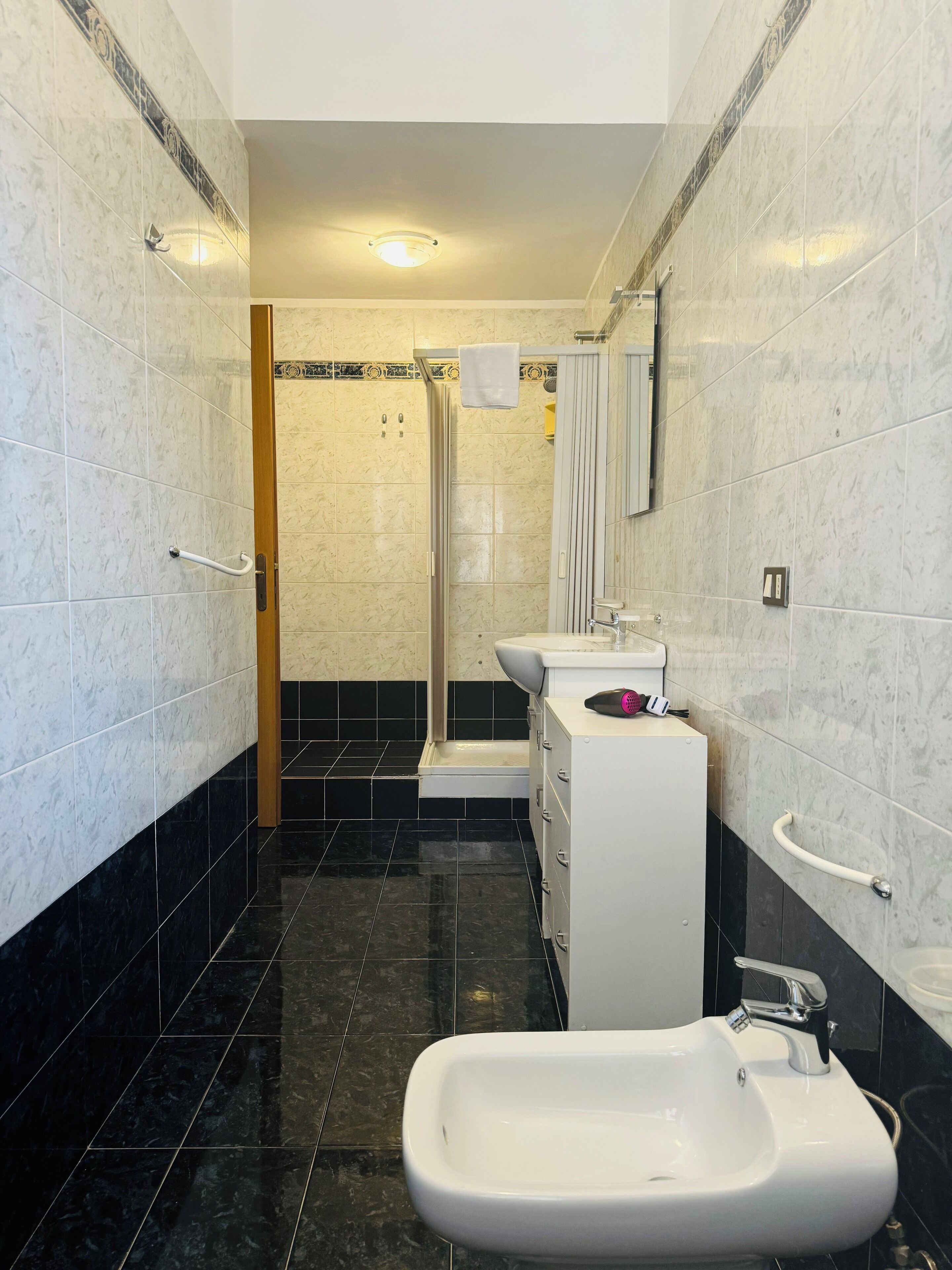 A modern bathroom with a bidet, a sink, and a shower area.