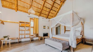 A bedroom with a canopy bed, wooden shelves, a TV, and a bench. - Zaria Garden Bungalow (Pwani Mchangani)