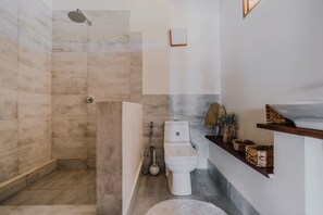 A modern bathroom with a shower, toilet, and a vanity with baskets. - Zaria Garden Bungalow (Pwani Mchangani)