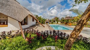 A resort with thatched-roof cottages, a swimming pool, and lush tropical landscaping. - Zaria Garden Bungalow (Pwani Mchangani)