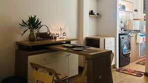 Une cuisine de taille réduite, avec un plan de travail en bois, un évier et un lave-linge à l’arrière-plan.