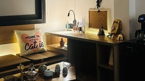 Une pièce confortable avec un lit, un bureau, une machine à café et une horloge fixée au mur.