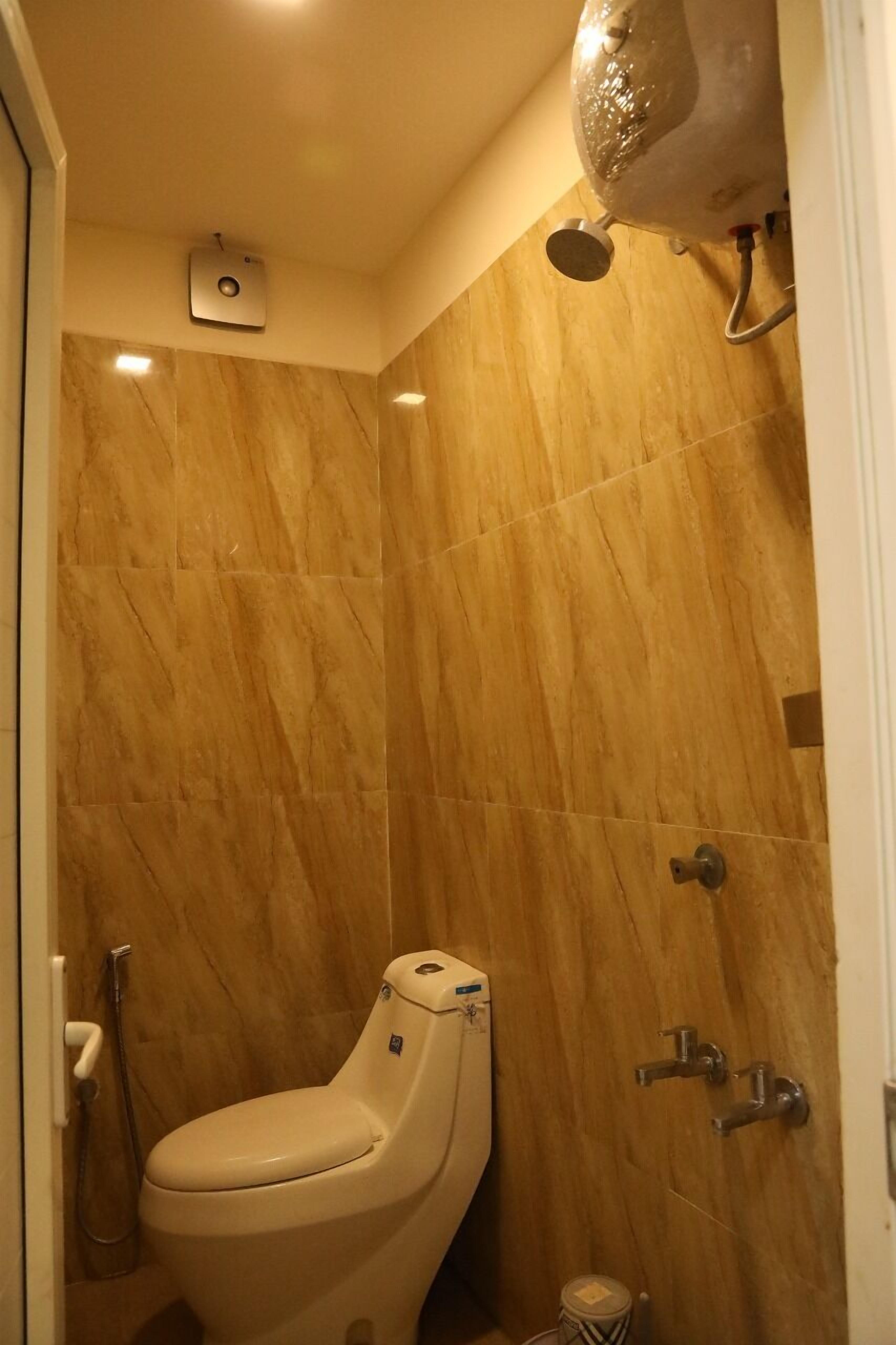 Une salle de bain équipée de toilettes, d’une douche et d’un radiateur fixé au mur.