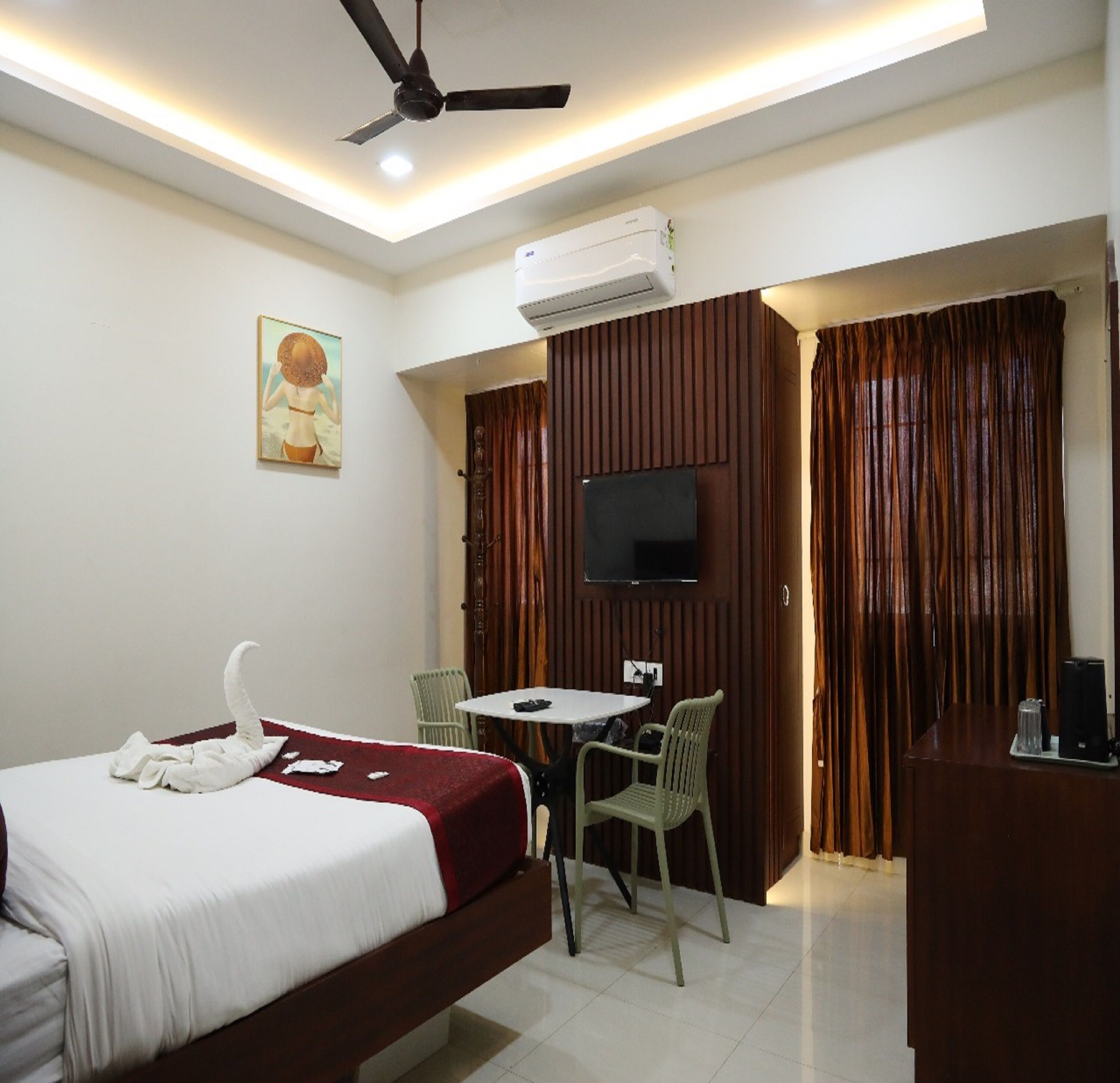 Une chambre d’hôtel comprenant un lit, une table à manger avec des chaises, un téléviseur et un appareil de climatisation.