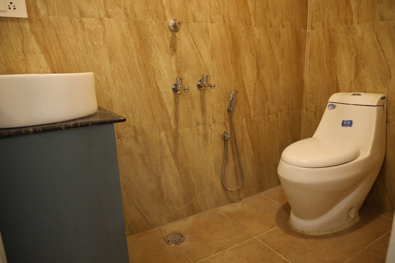 A bathroom with a white toilet, a sink, and a shower with a handheld showerhead.