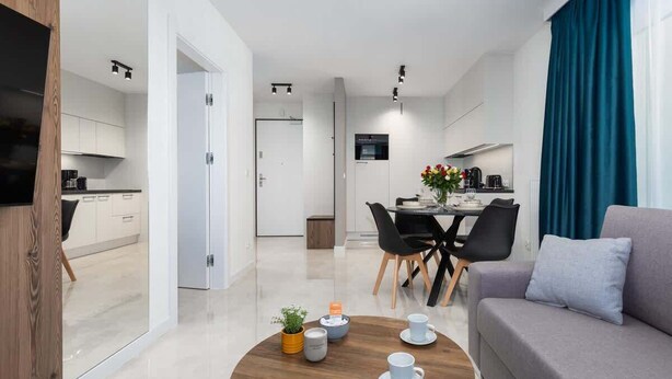 A modern living room with a sofa, coffee table, and dining area.