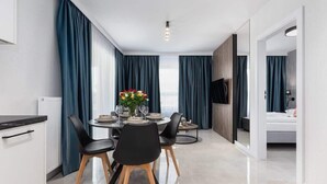 A modern dining area with a round table, black chairs, and a vase of flowers.