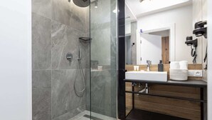 A modern bathroom with a glass-enclosed shower, a wooden vanity with a sink, and a mirror.