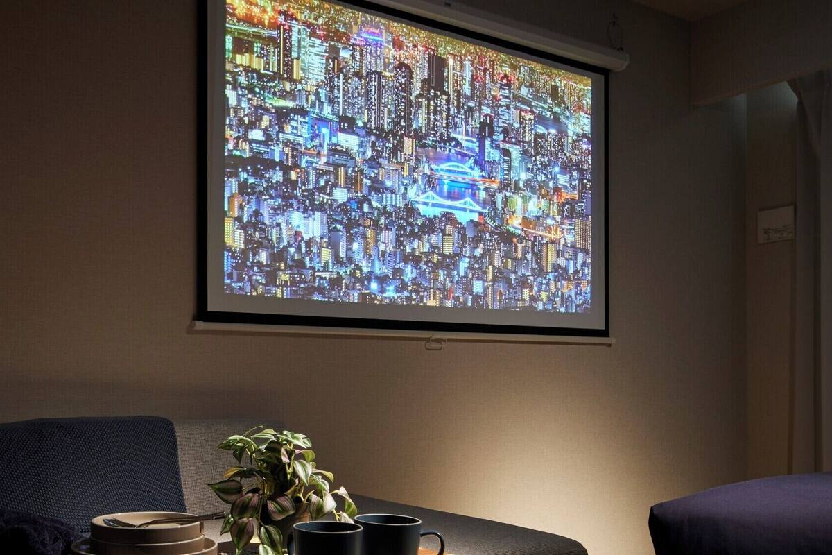 Une projection d’un paysage urbain sur un mur, une plante et une table avec des tasses et une assiette.