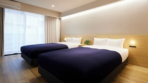 A hotel room with two beds, a large window with curtains, and a wooden floor.
