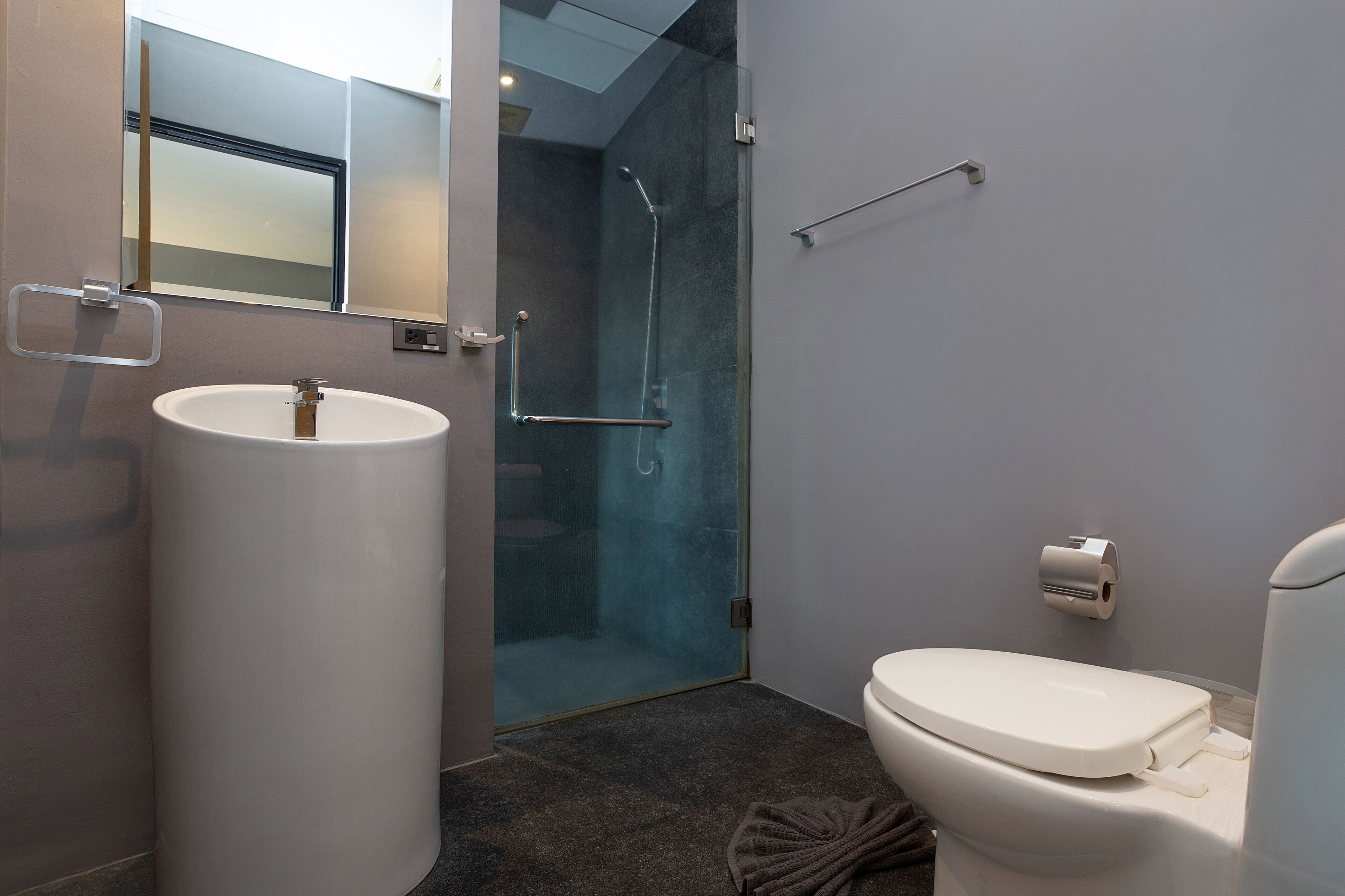 A modern bathroom with a large sink, toilet, and glass-enclosed shower.