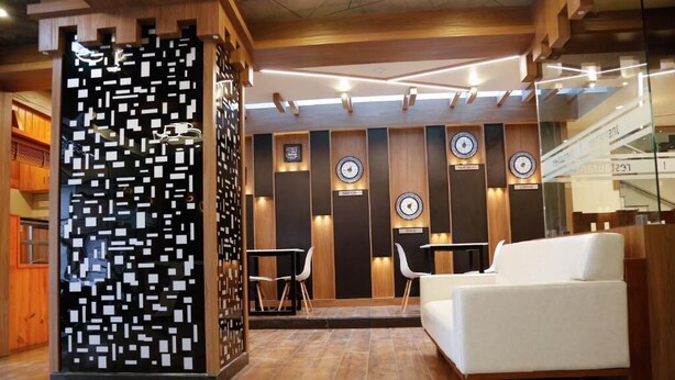 Um hall moderno com um sofá branco, uma divisória decorativa em preto e branco e vários relógios na parede.