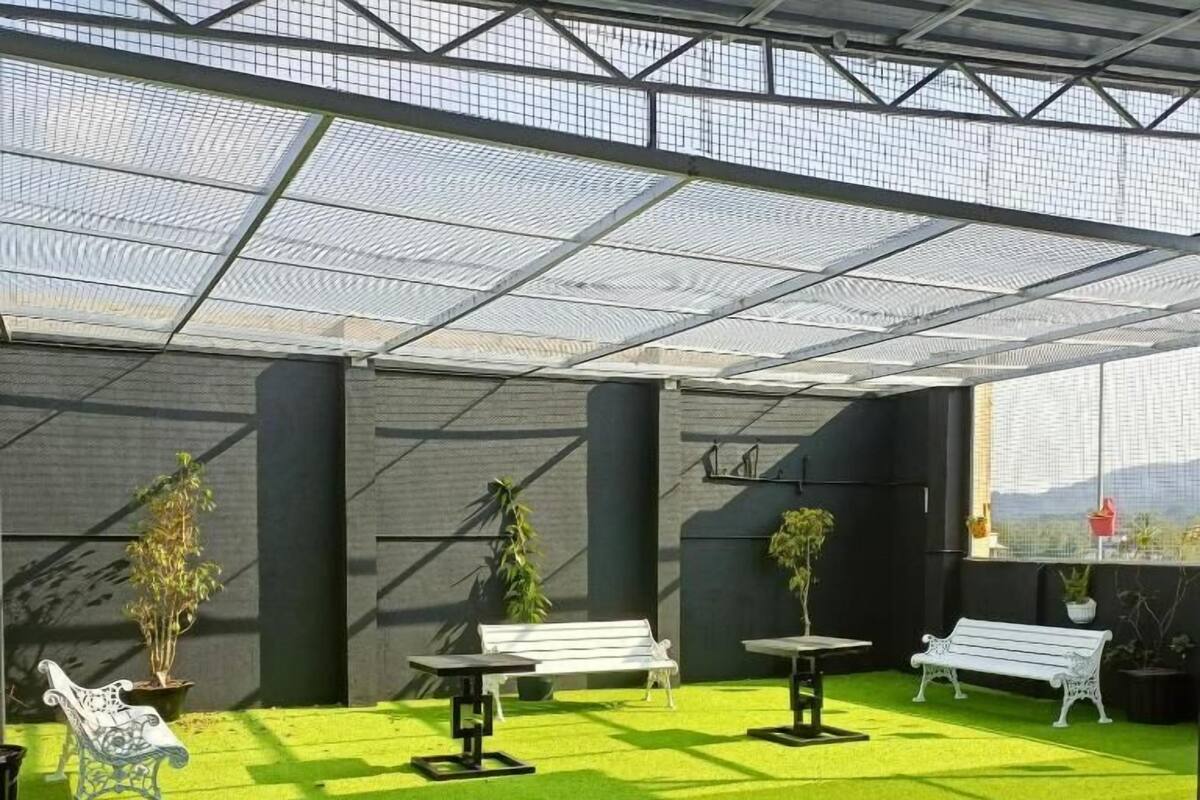 A covered outdoor area with artificial grass, benches, and potted plants.