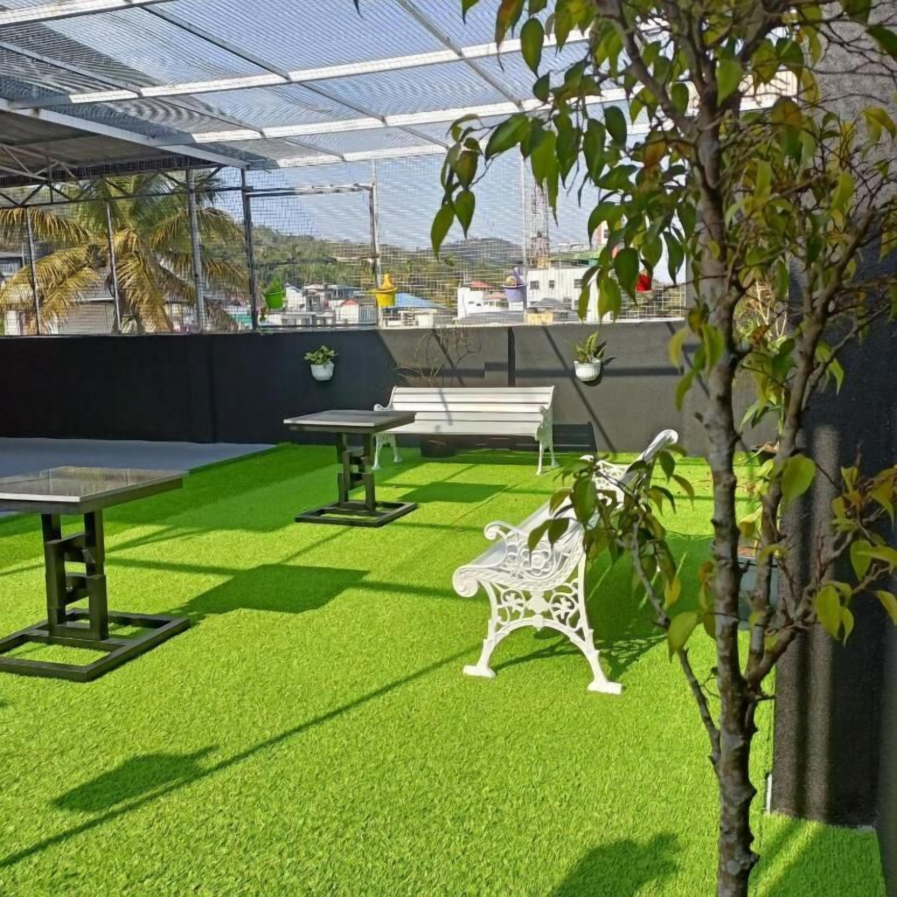Un patio al aire libre con césped artificial, una mesa, un banco y plantas en macetas.