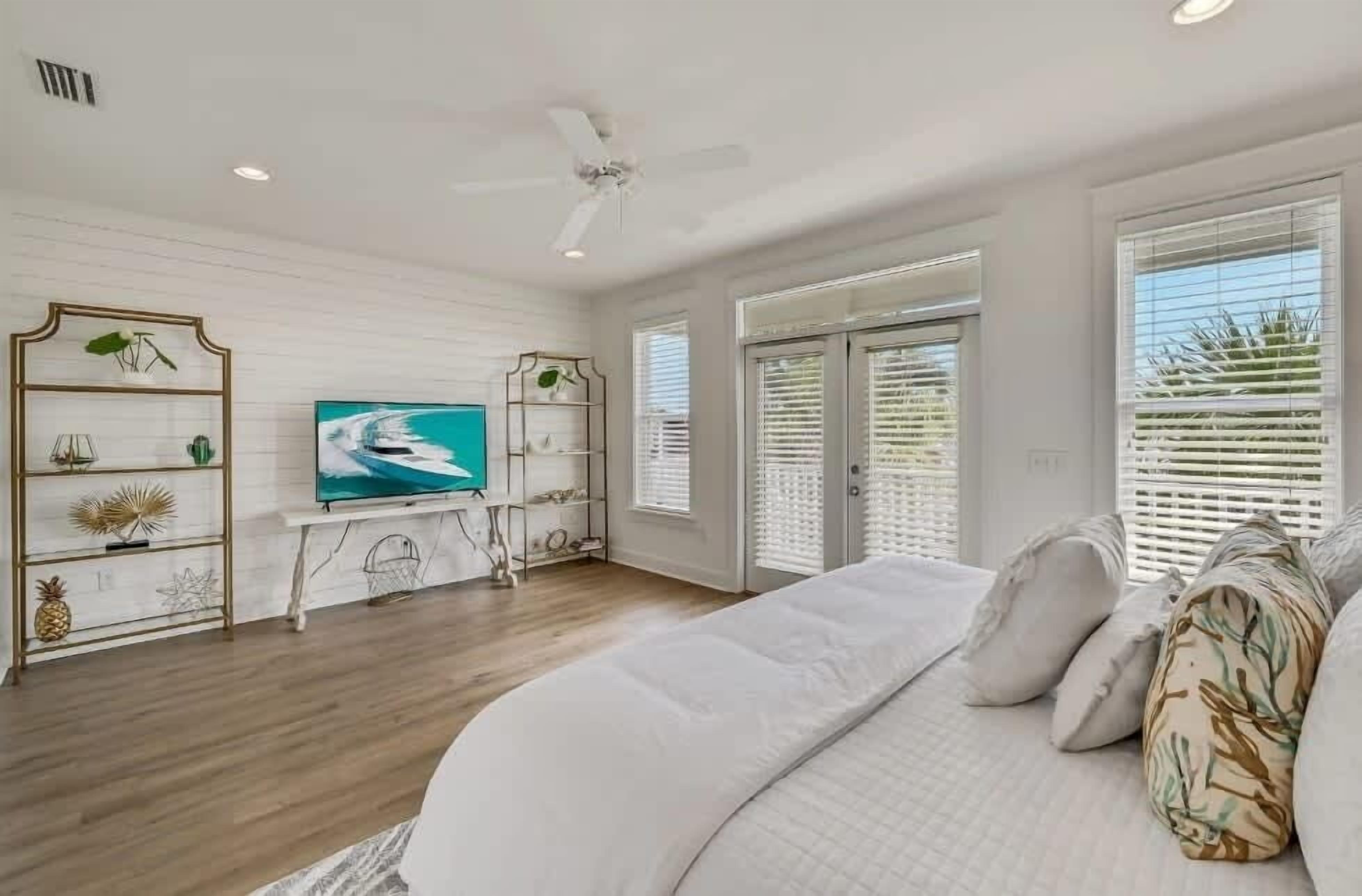 A bedroom with a large bed, a TV, and a ceiling fan.