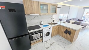 A compact kitchen with a refrigerator, stove, oven, dishwasher, and washing machine.