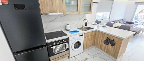 A compact kitchen with a refrigerator, stove, oven, dishwasher, and washing machine.