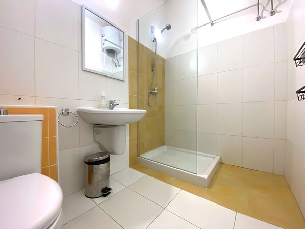 A bathroom with a toilet, sink, and glass-enclosed shower. - Miami Apartments (St. Julian's)
