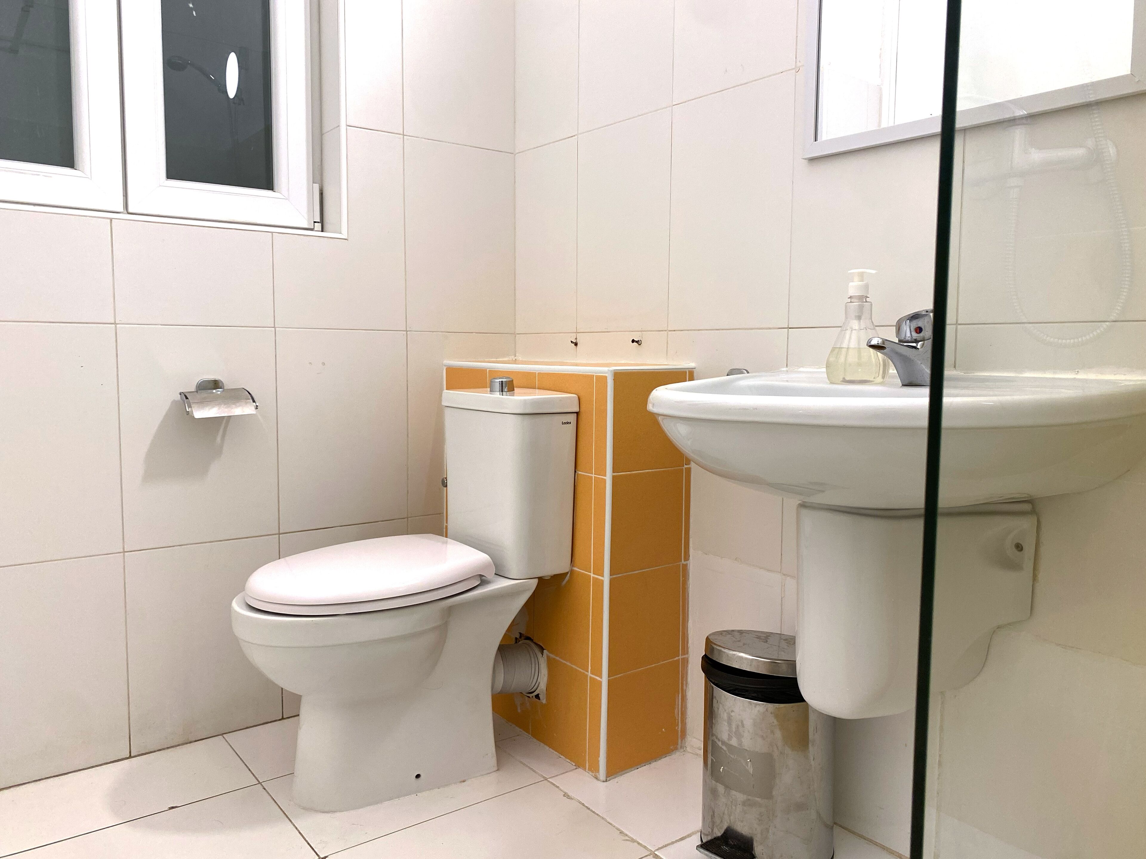 Un baño con inodoro, lavamanos y un cubo de basura.