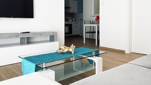 A modern living room with a glass coffee table, a sofa, and a TV mounted on the wall. - Miami Apartments (St. Julian's)