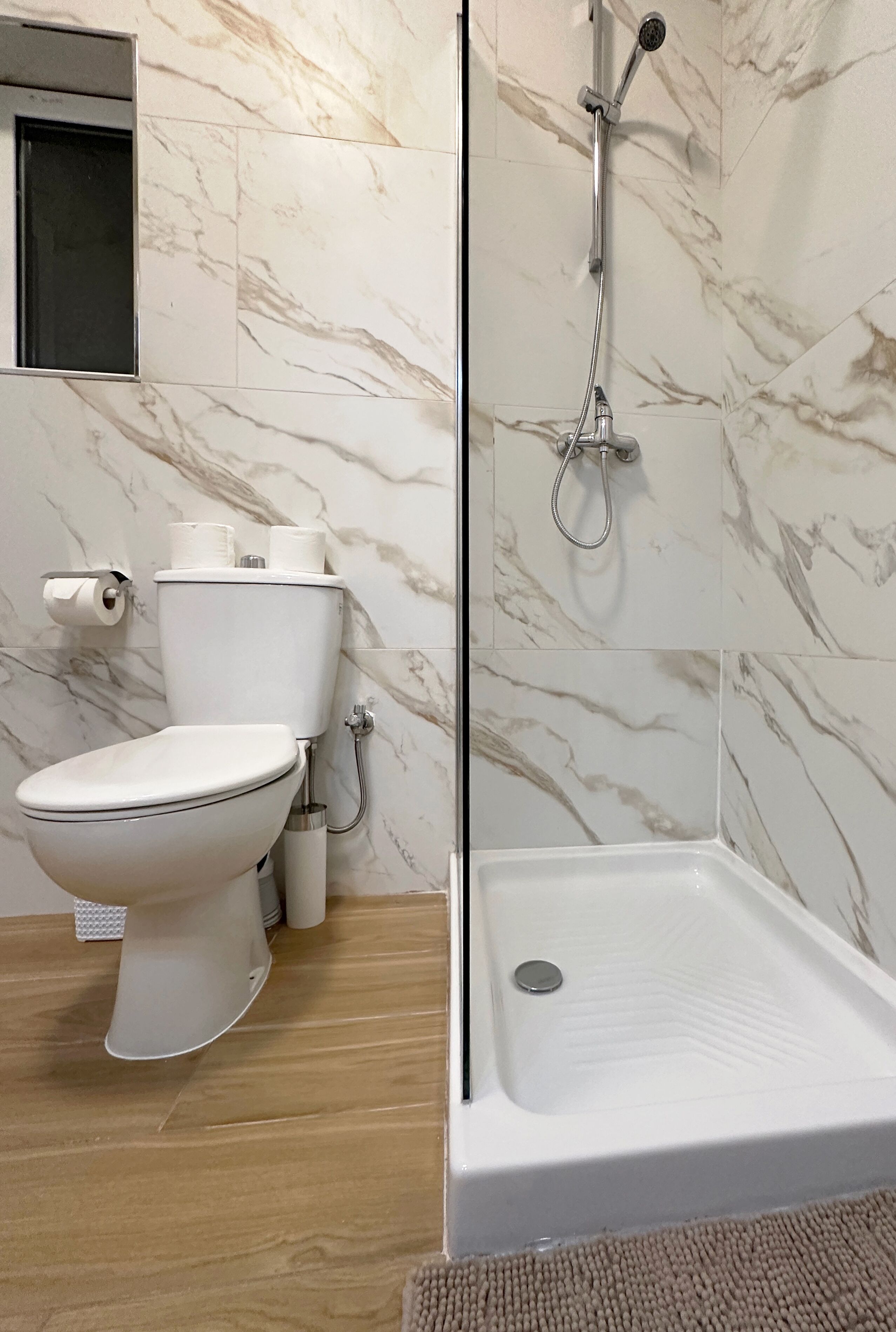 Une salle de bain avec des toilettes, une douche et des murs en marbre.