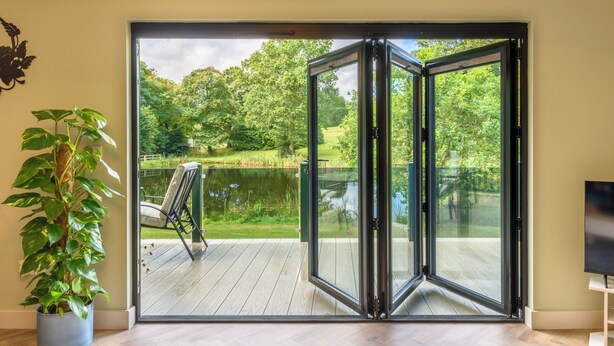 Une pièce dotée d’une porte-fenêtre coulissante donnant sur une terrasse avec un bassin et de la verdure.