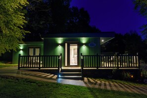 A green building with a porch and a sign that reads "Spring Mountain." - Secret Waterside Lodges in Worcestershire (Worcester)