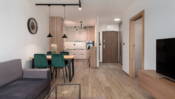 A modern living room with a sofa, a glass coffee table, and a TV on a wooden stand. - Pure Rental Premium Apartments (Wroclaw)