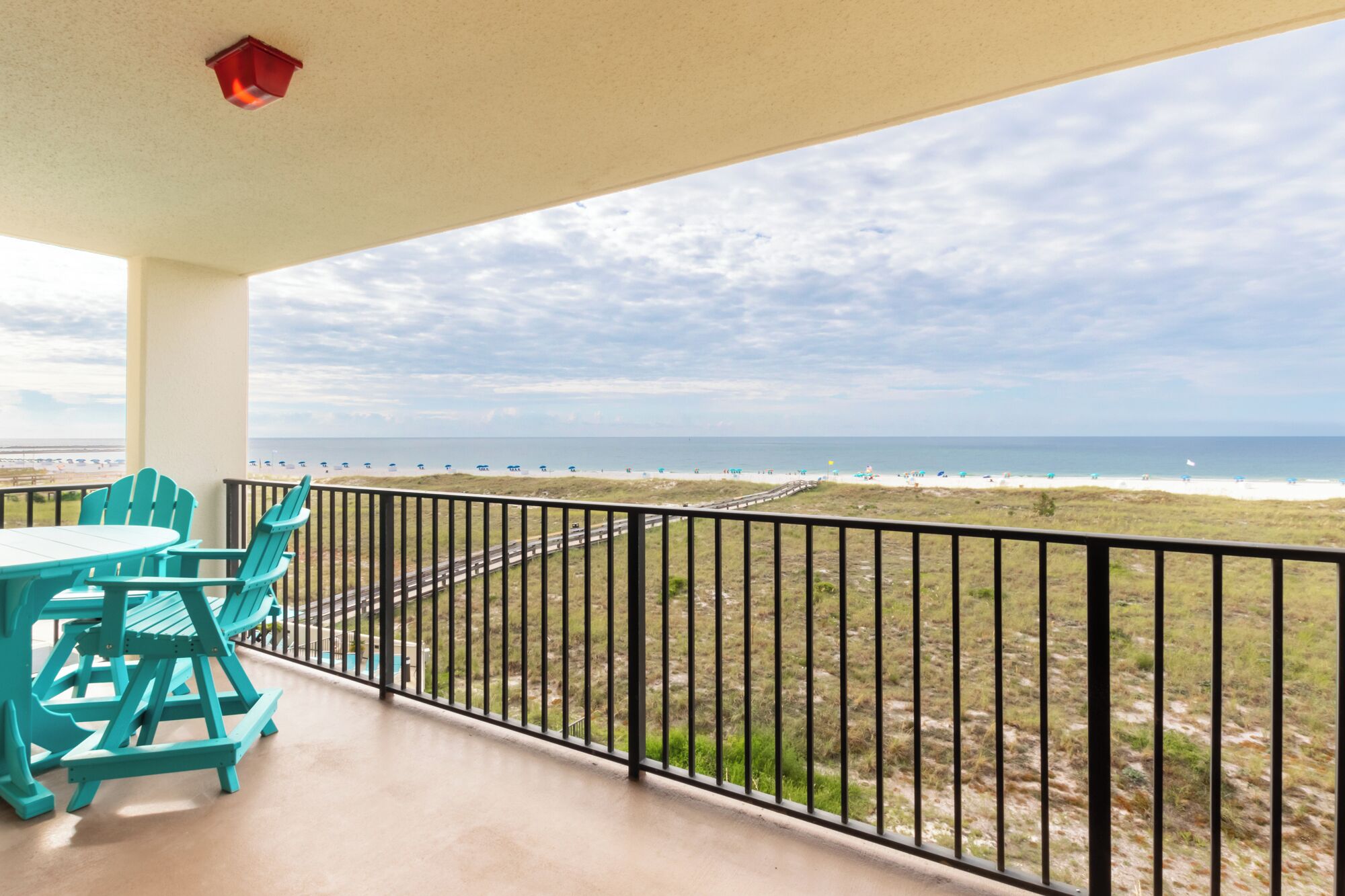 Un balcon avec vue sur la plage, une table et des chaises.