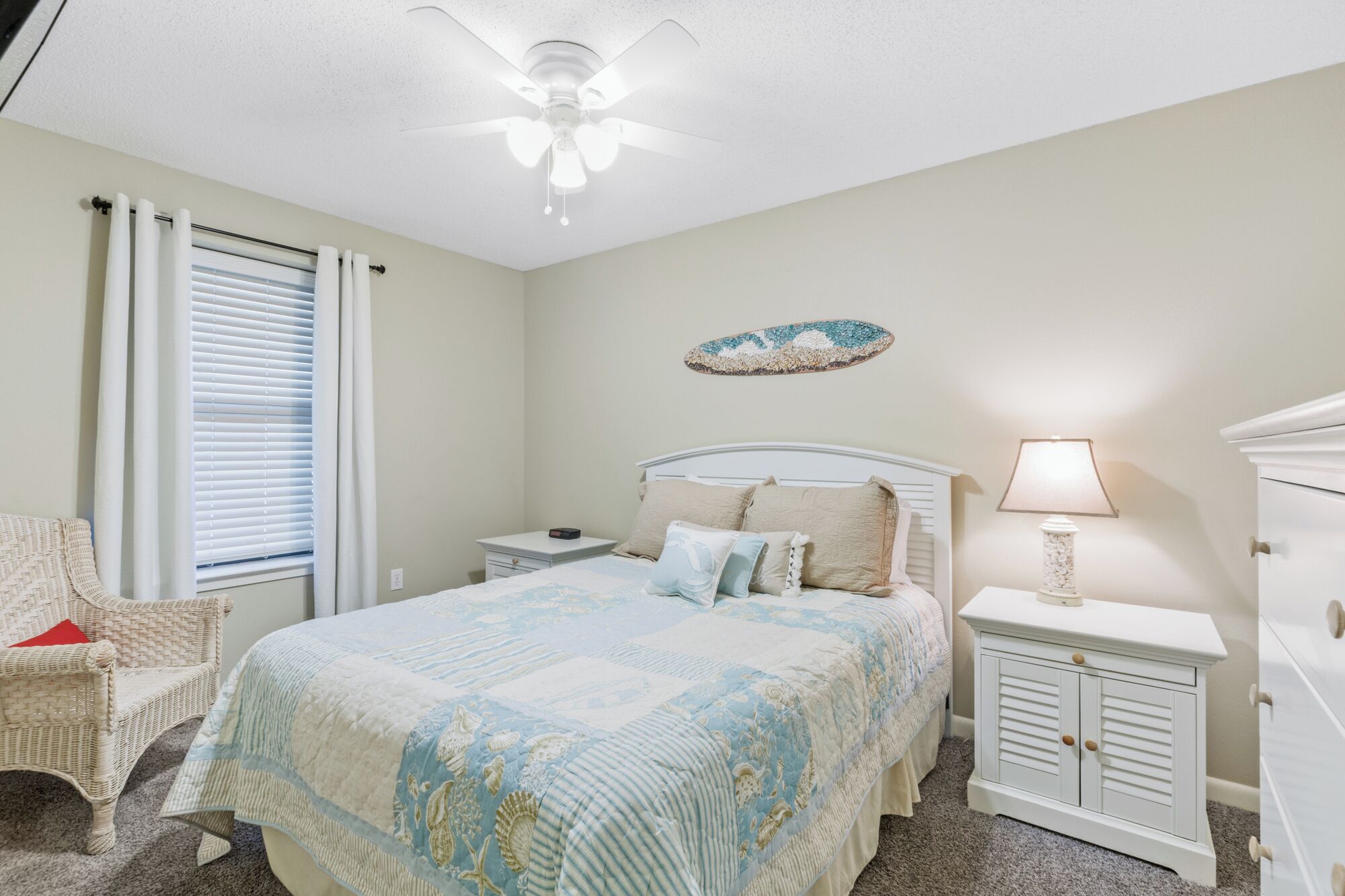 A bedroom with a bed, nightstand, dresser, and a ceiling fan.