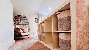 A room with a rattan chair, built-in storage with woven baskets, and a carpeted floor. - Mins to Stadiums - Spacious & Elegant (Pittsburgh)