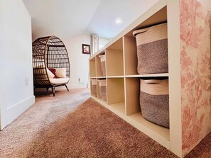 A room with a rattan chair, built-in storage with woven baskets, and a carpeted floor. - Mins to Stadiums - Spacious & Elegant (Pittsburgh)