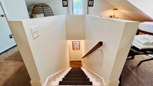 A staircase with a checkered carpet leading to a landing with a framed picture. - Mins to Stadiums - Spacious & Elegant (Pittsburgh)