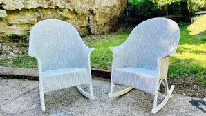 Two white wicker rocking chairs on a gravel surface with a stone wall and greenery in the background. - Mins to Stadiums & Steps to Northside and AGH (Pittsburgh)