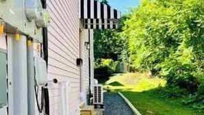 A building with a gravel pathway leading to a door with a black and white striped awning. - Mins to Stadiums & Steps to Northside and AGH (Pittsburgh)