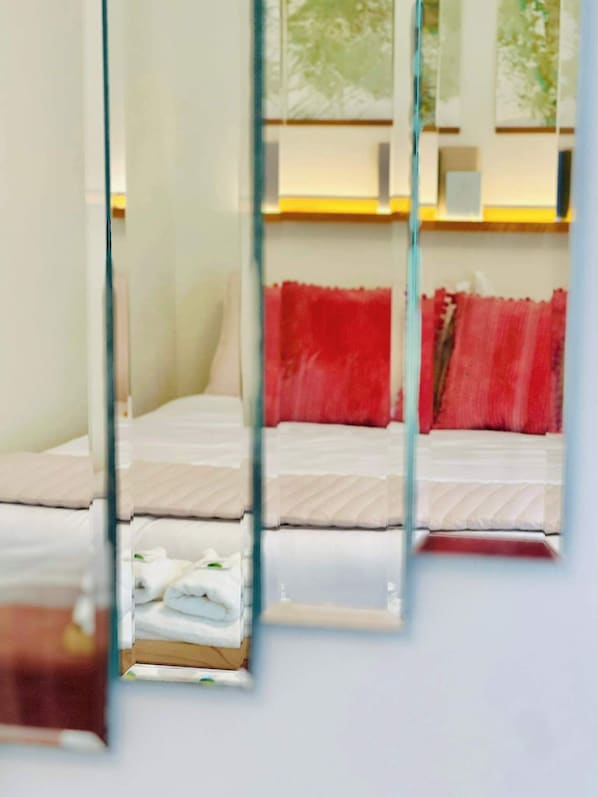 Una habitación de hotel con una cama, un cojín rojo y un ventanal con vistas.