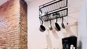 A kitchen with a brick wall, wooden cabinets, and a hanging pot rack. - Mins to Stadiums & Steps to Northside and AGH (Pittsburgh)