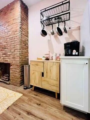 Una cocina con pared de ladrillo, armarios de madera y un colgador para ollas.