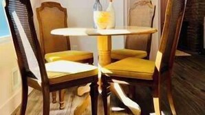A dining area with a round table and four chairs, a vase with flowers, and a brick wall in the background. - Mins to Stadiums & Steps to Northside and AGH (Pittsburgh)