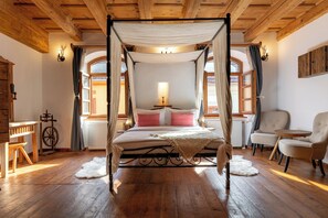 A four-poster canopy bed with a bedside table and lamp, wooden flooring, and a seating area with chairs. - Boutique Hotel von Graf (Sighisoara)