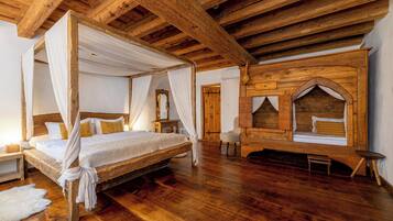 A four-poster bed with a canopy, wooden flooring, and a rustic wooden wall with a built-in bench.