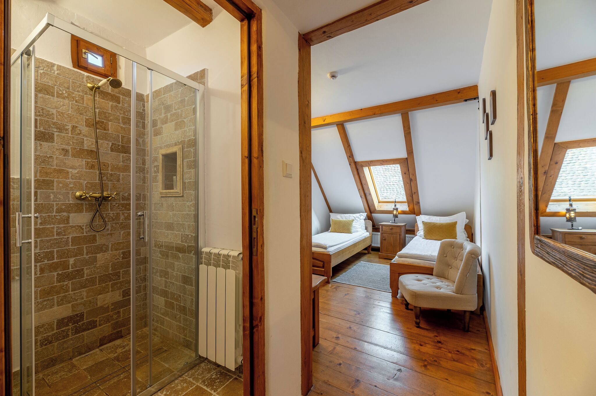 Ein Schlafzimmer mit Schlafplatz im Stil einer Loftswohnung, einer kleinen Sitzecke und einer Duschkabine aus Glas.