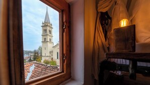 A window with a view of a church tower and a tiled roof. - Boutique Hotel von Graf (Sighisoara)