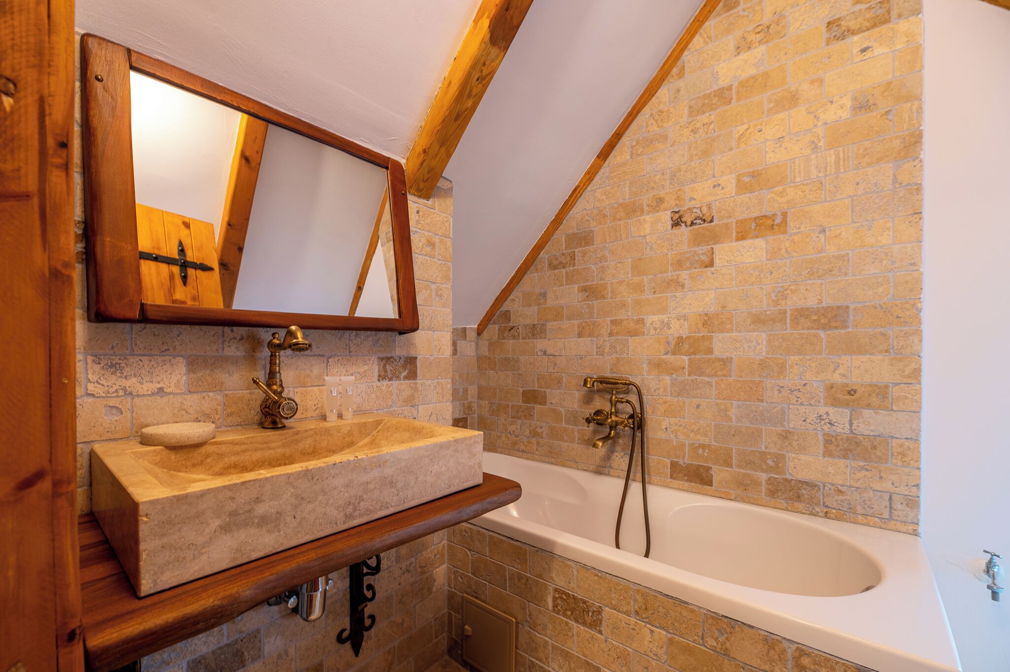Un baño con tocador de madera, un espejo grande y una bañera con pared de azulejos.