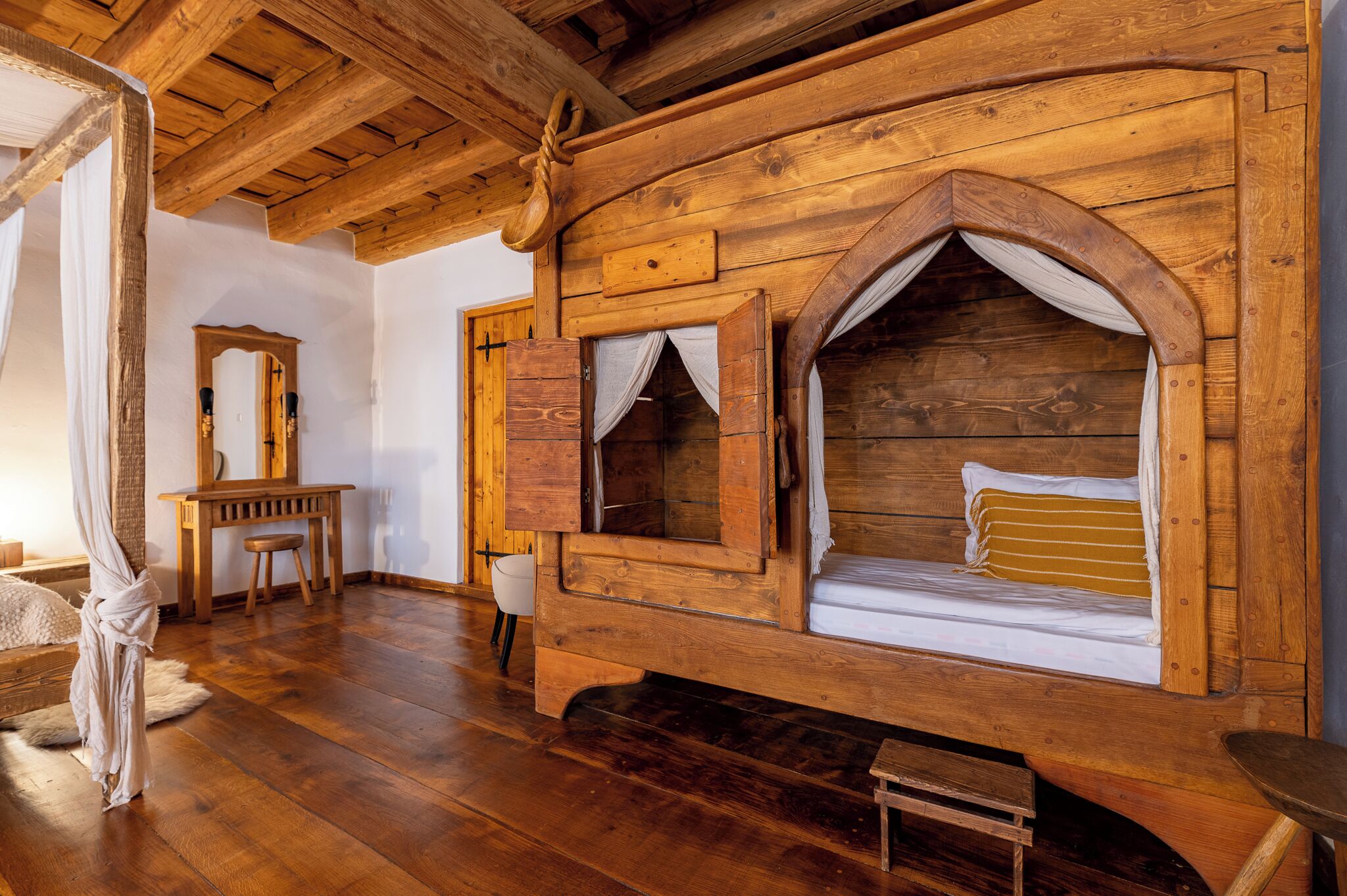 Une pièce rustique en bois, avec un lit, un bureau en bois et un miroir.