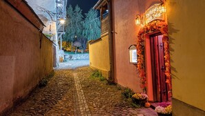 A cobblestone alleyway with a building featuring a red door and a sign above it. - Boutique Hotel von Graf (Sighisoara)